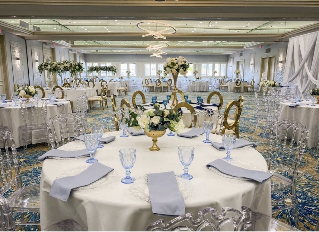 ballroom set up for a banquet with round tables, napkins, glasses, and floral centerpiece