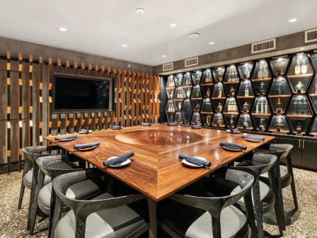 private room with tv, square, wooden table and grey chairs at puesto park place irvine