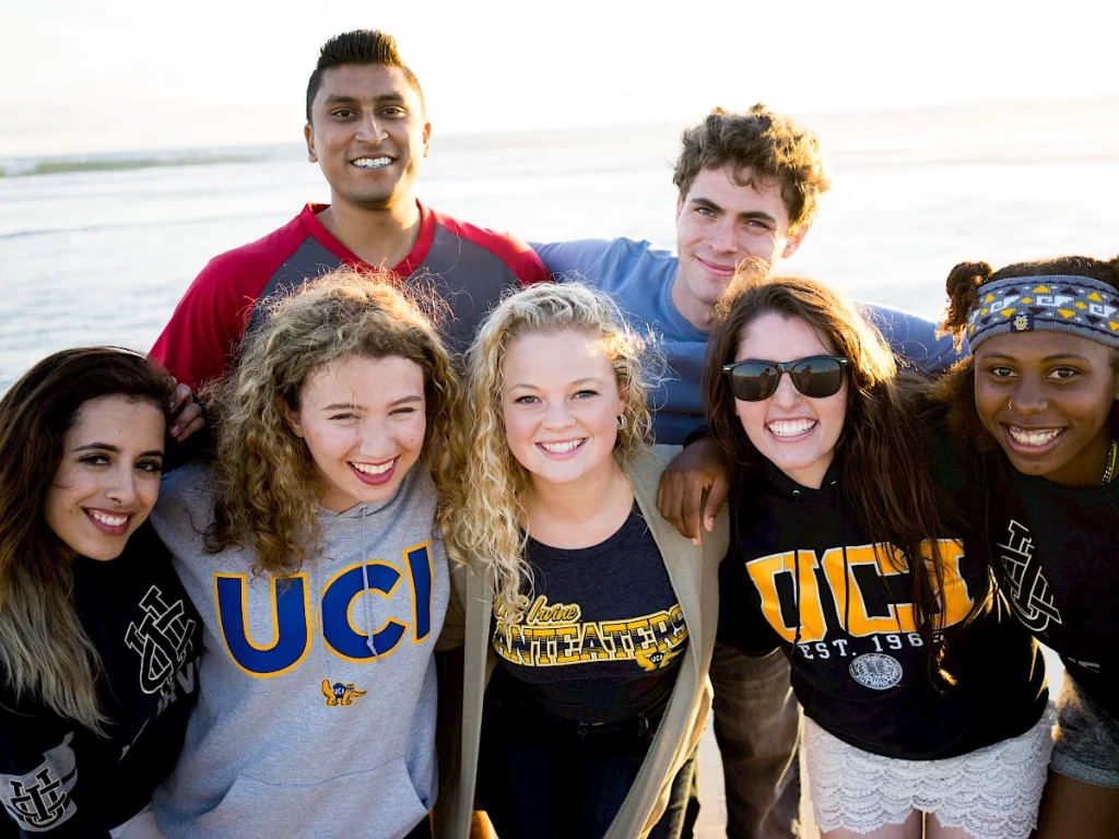 seven students wearing uci sweaters at the beach