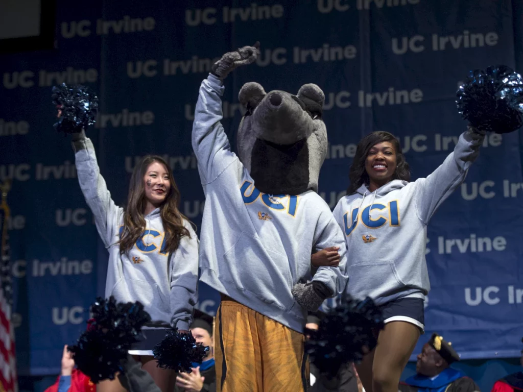 two cheerleaders in uci sweaters with uci mascot peter the anteater