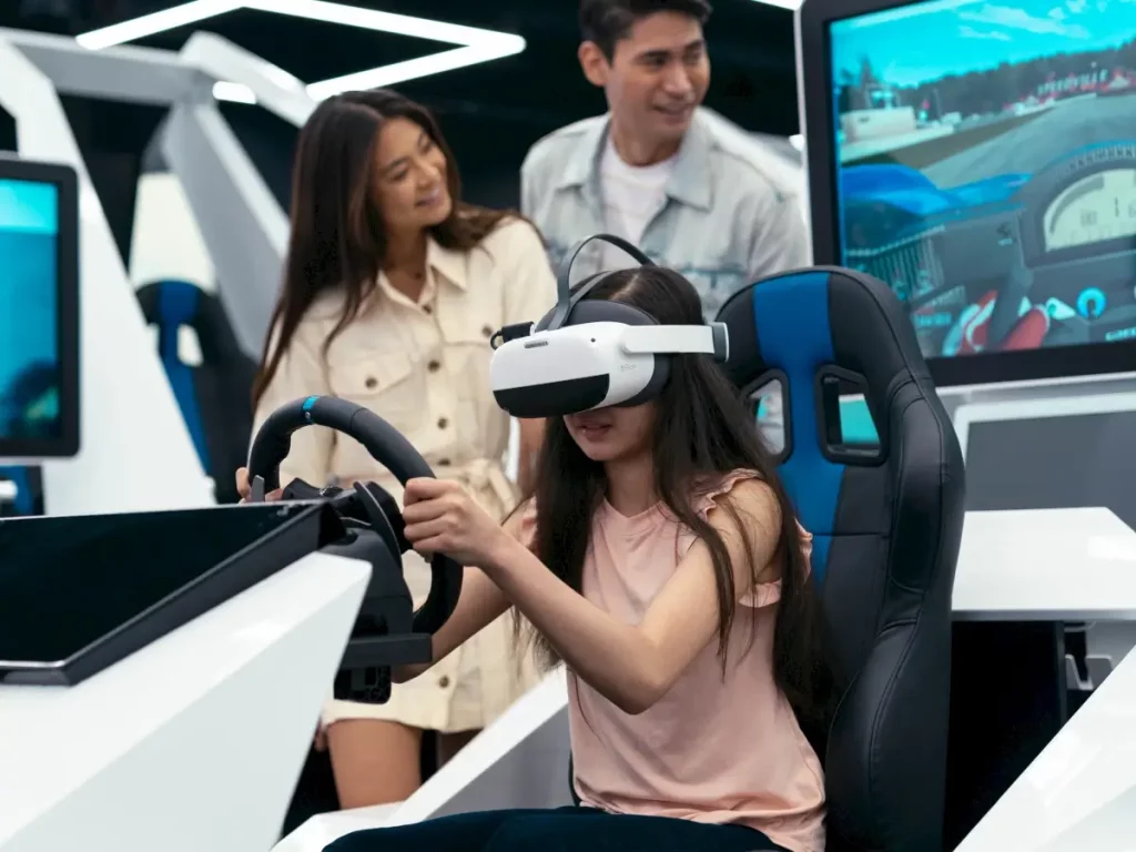 A young girl plays a vr racing game as her parents watch behind her