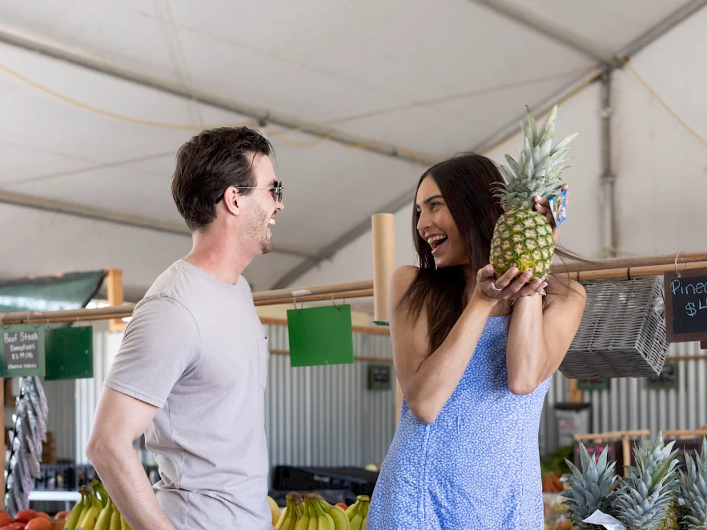 man laughing and woman holding a pineapple at tanaka farms