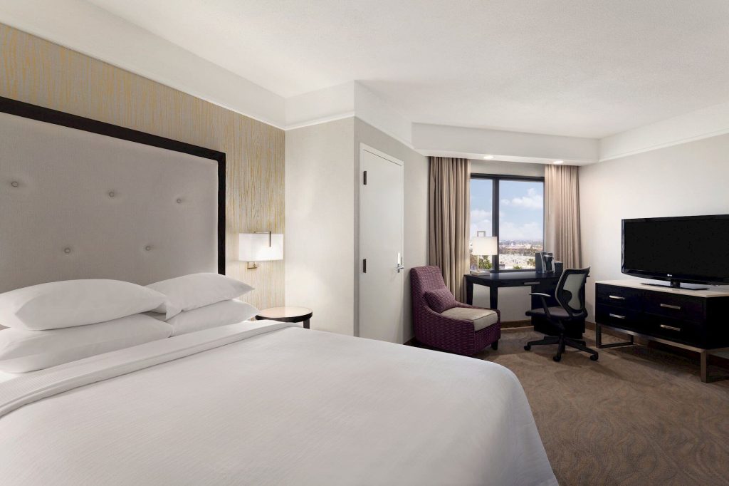 hotel room with bed, tv, tv stand, lamp, desk, two chairs at embassy suites irvine