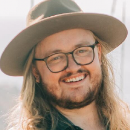 long haired musician mark desmond in hat and glasses smiling