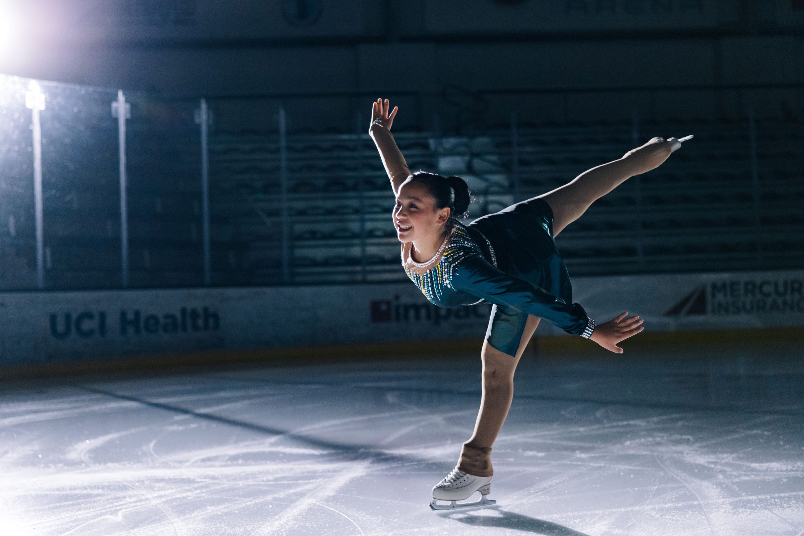 female skater in green dress gliding through the ice rink