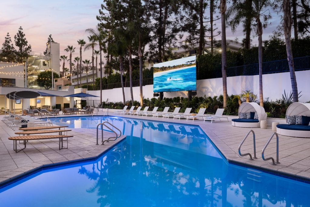 pool area with large tv and chair lounges at irvine marriott hotel during night time