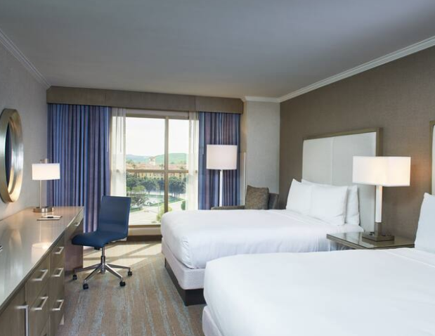 hotel room with blue chair and two white beds at doubletree spectrum