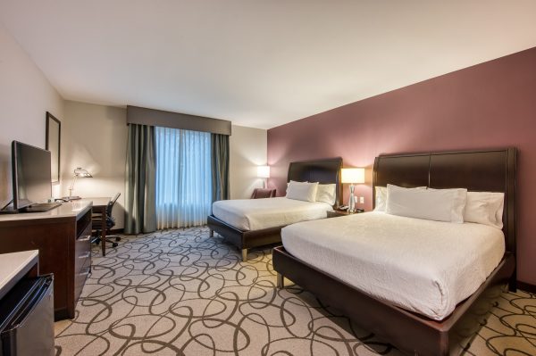 hotel bedroom with two queen beds and tv with hilton garden inn