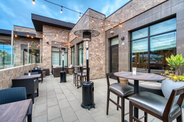 outdoorr patio with string lights, tables, chairs and heaters at hilton garden inn hotel in irvine