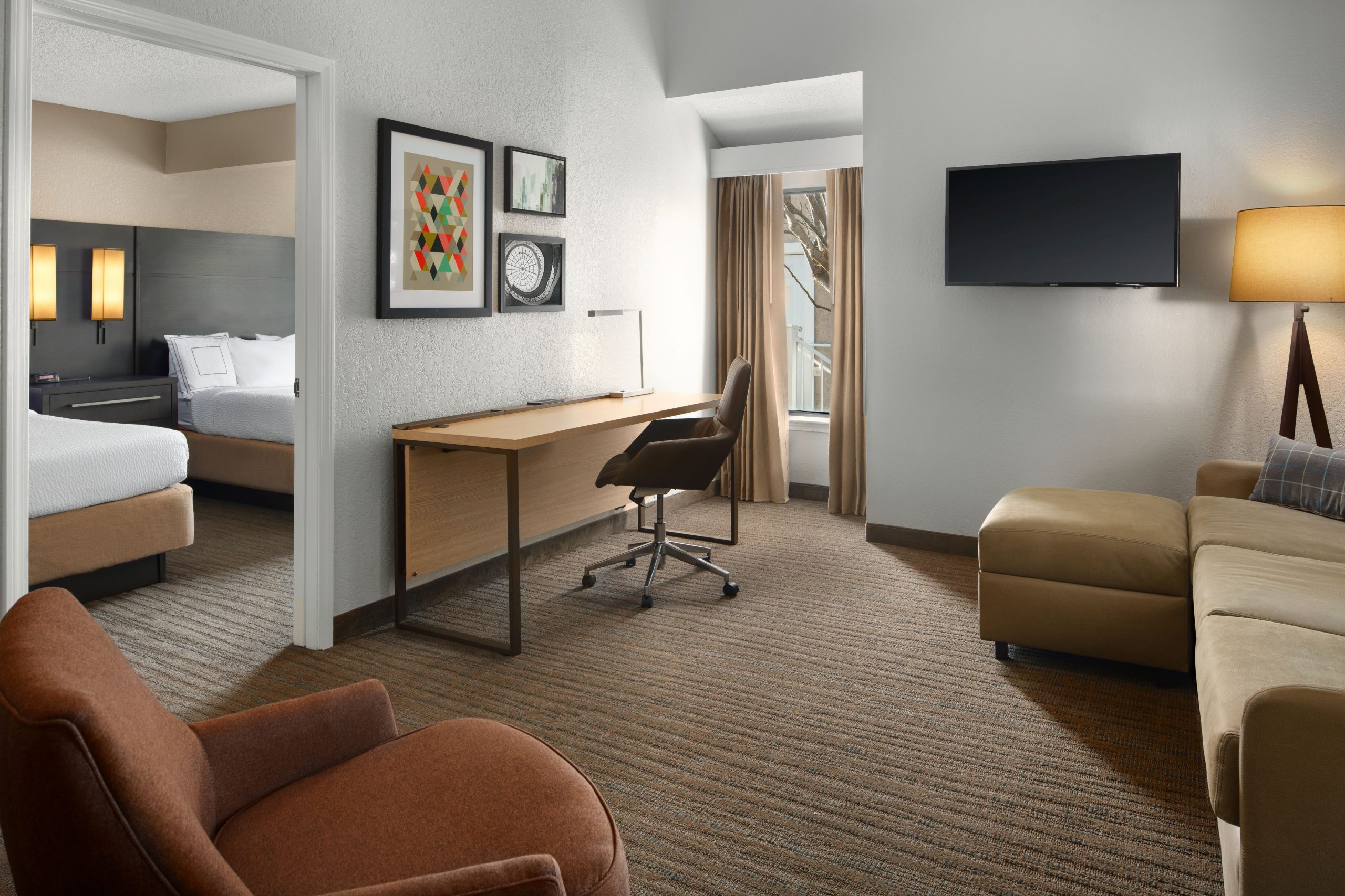 room suite at residence inn irvine spectrum with 2 beds desk chair sofa lamp and picture frames on the wall