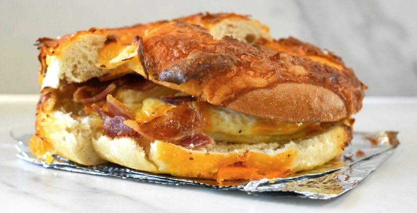 sandwich with toasted cheese on top and bacon, egg and cheese inside from the bagel shack