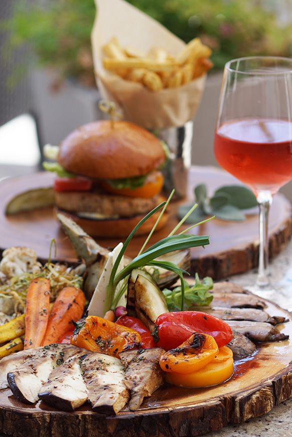 table with plate of vegetables and a plate with burger and fries and a red drink at andrei's restaurant