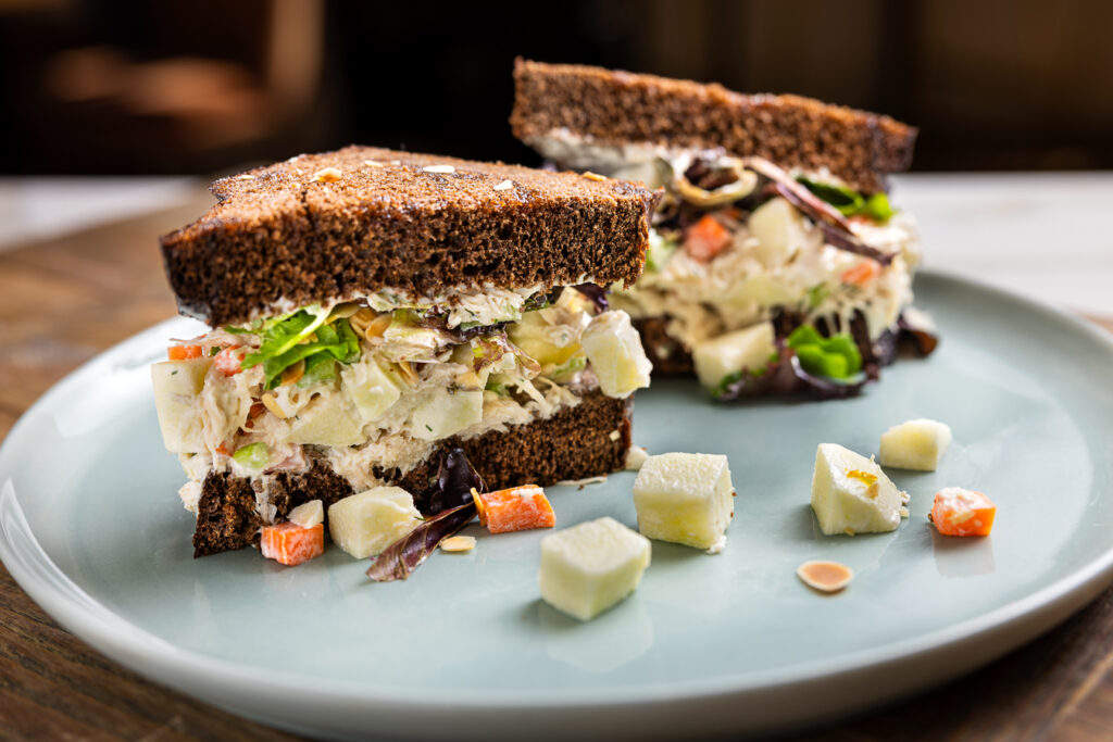 a plate of sandwich with rye bread filled with potatoes and vegetables