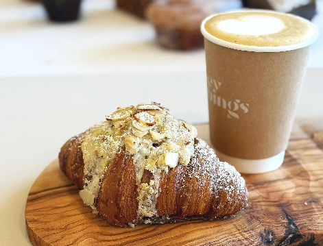 croissant with almond glaze and a cup of coffee with heart shaped foam