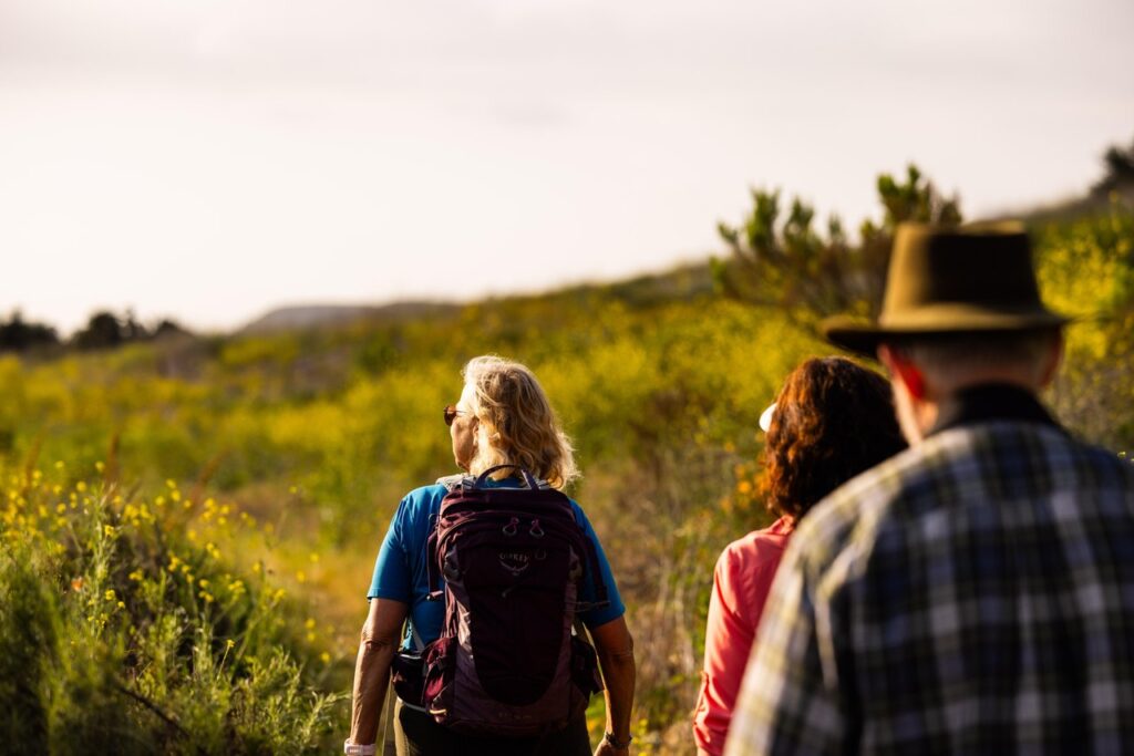 three hikers, two women and one man with a hat, hiking at bommer canyon irvine