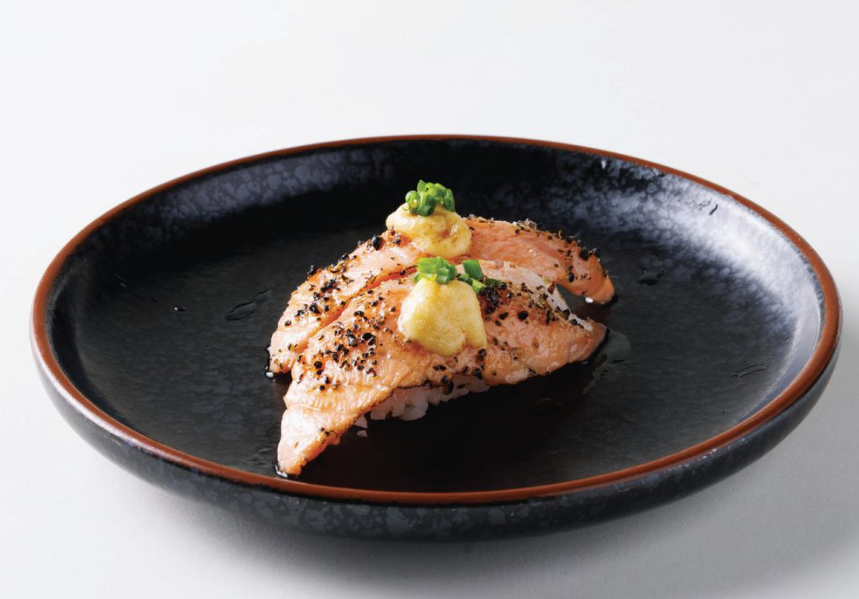 two pieces of salmon sushi on a black plate