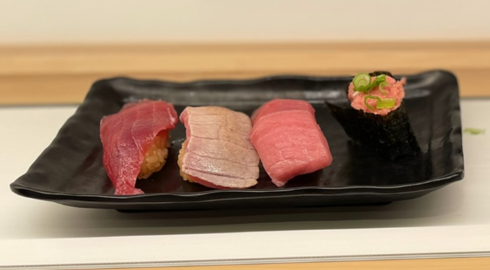 four sushi pieces on a black sushi plate
