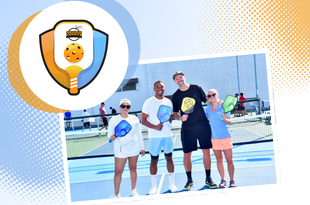 two men and two women in sports shorts and shirts holding a pickleball paddle in a pickleball court with an artwork on the top left of a pickleball with the logo of orange county sports commission