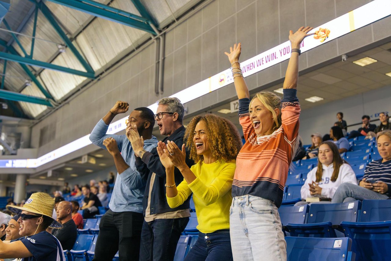 group of four friends, two males, two females cheering while standing on