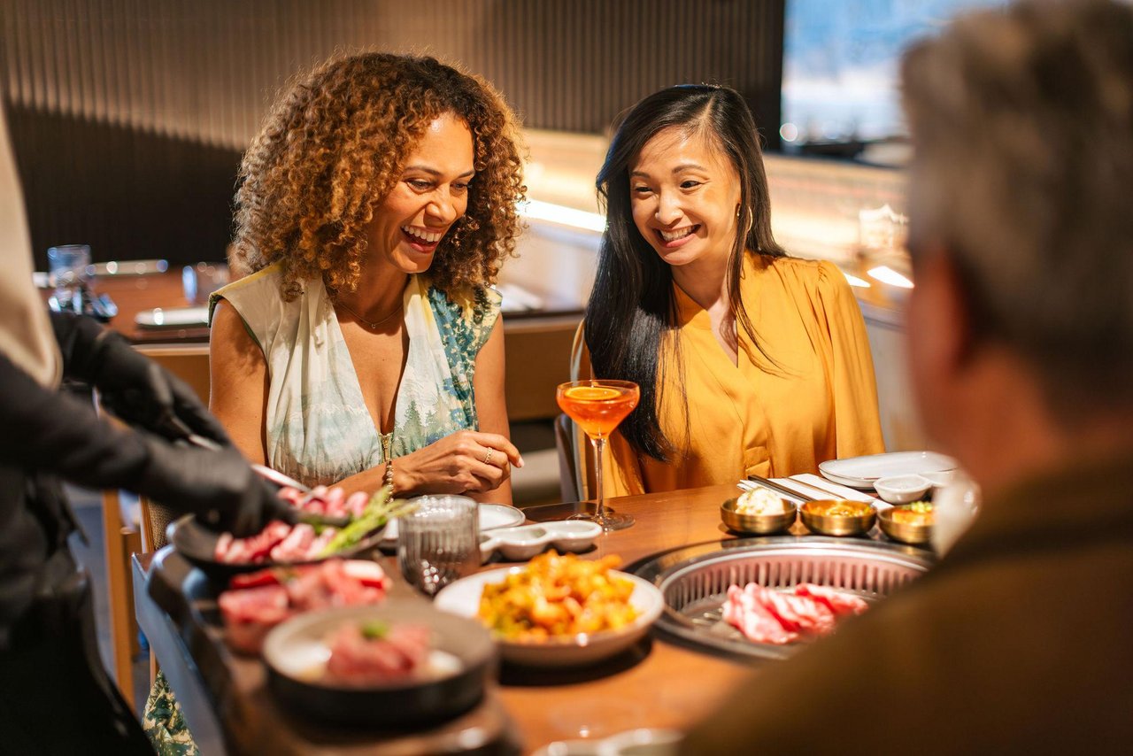 two women at a restaurant smiling enjoying the food presentation at the table