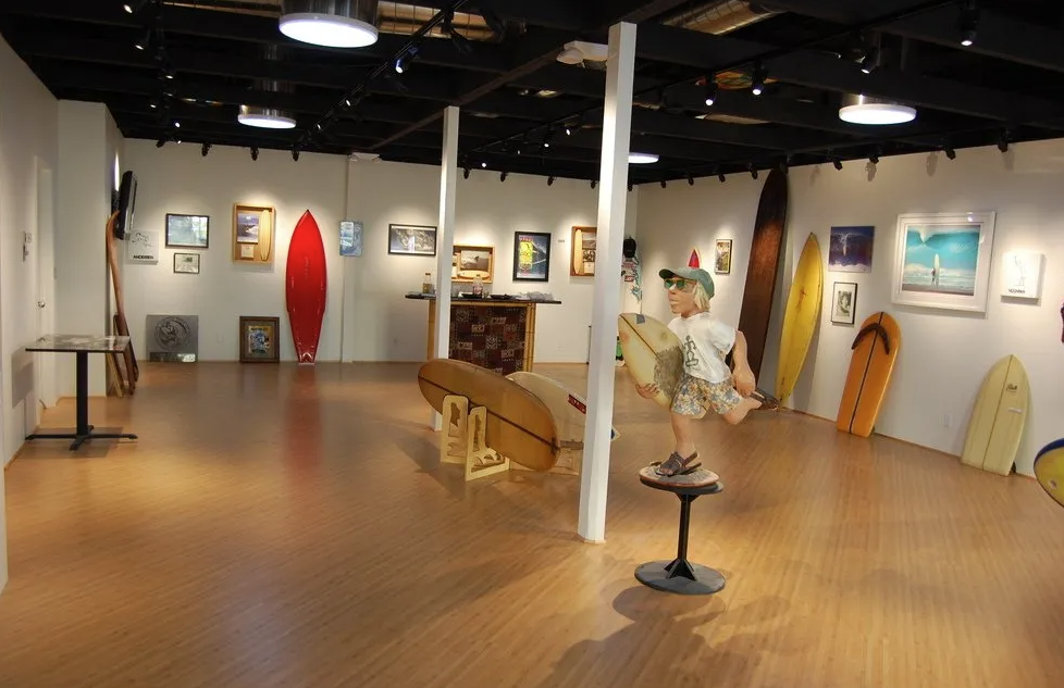 an indoor exhibit of surfboards and a few photographs and paintings of the beach