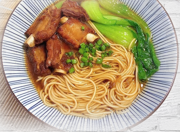 a bowl of noodles with greens and beef