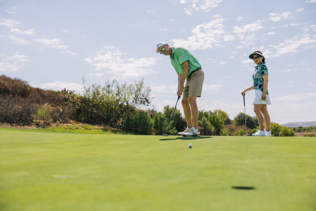 male and female golfer putting on a golf course on a sunny day