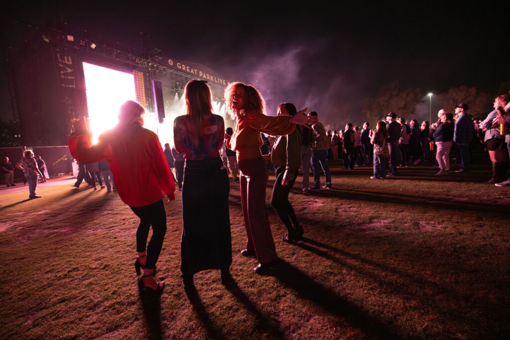 Three ladies standing smiling at an outdoor event venue at night