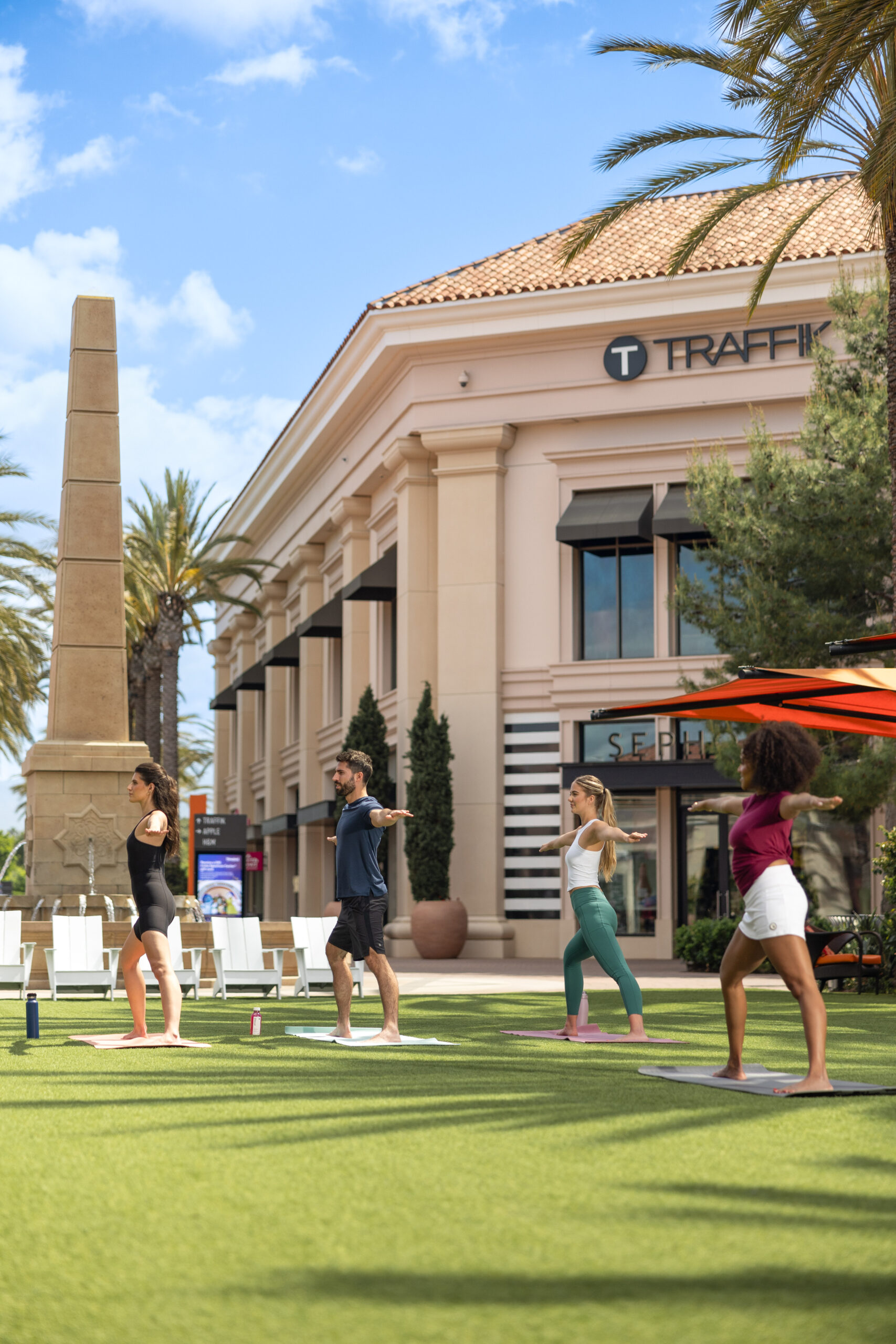 3 females and 1 male doing yoga on the lawn at irvine spectrum center