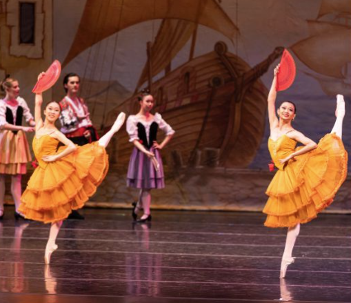 dancers holding red fans in orange dresses performing ballet onstage at irvine barclay theater