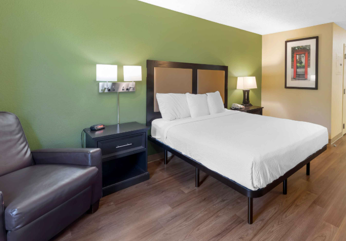 room with white bed and green wall painting