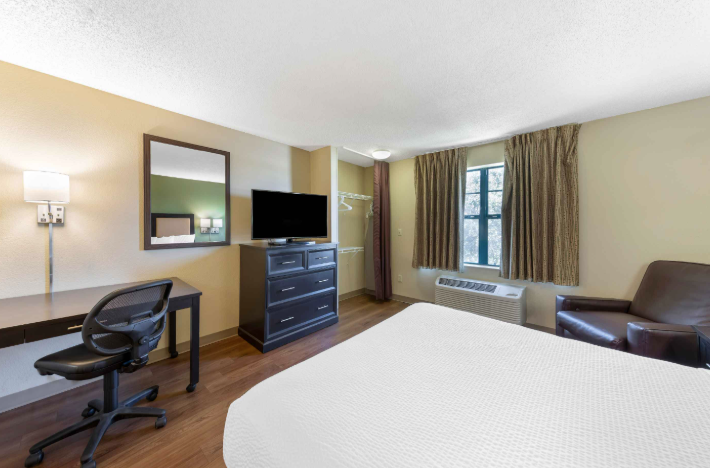 hotel room with tv, mirror and white bed