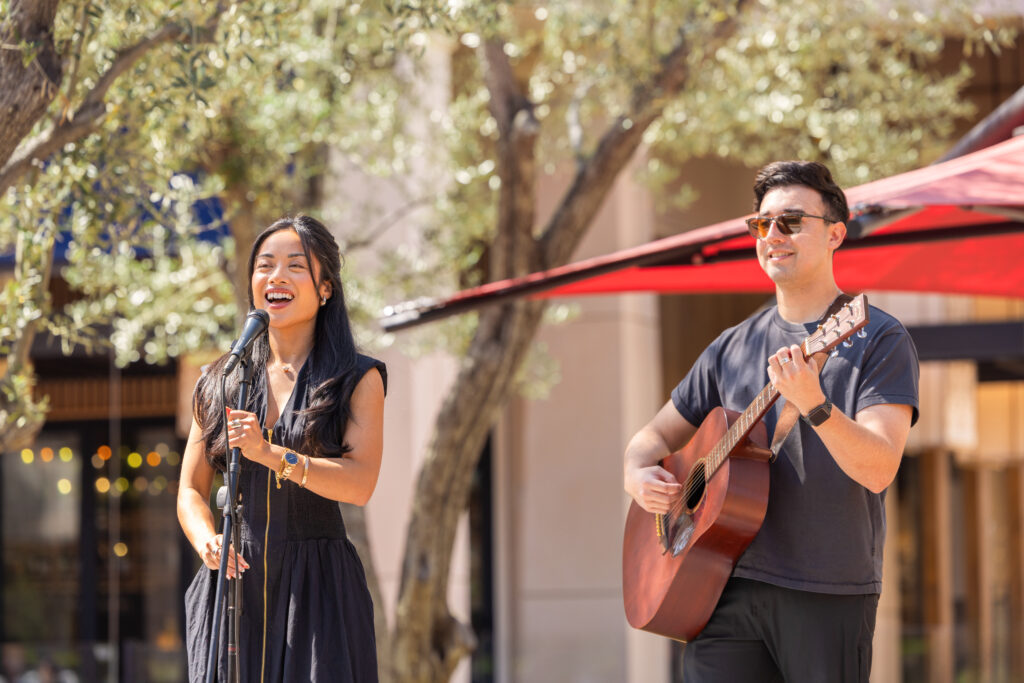 female singer and male guitarist performing outdoors on a sunny day at irvine spectrum center