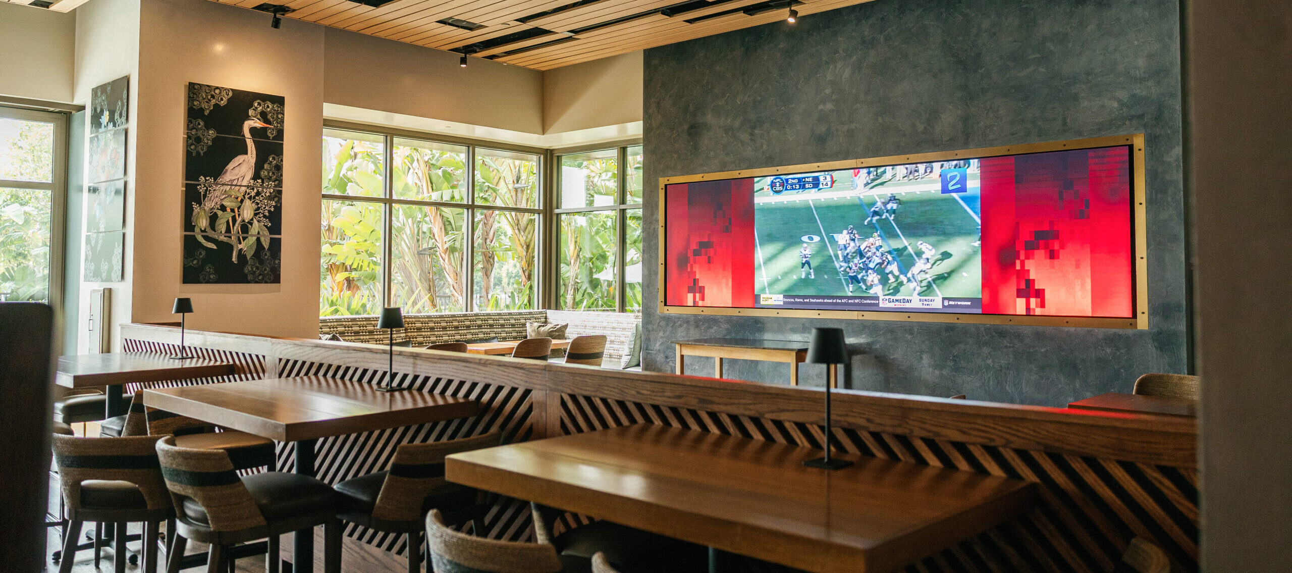 hotel lobby with sofas, high tops, tables and a big screen
