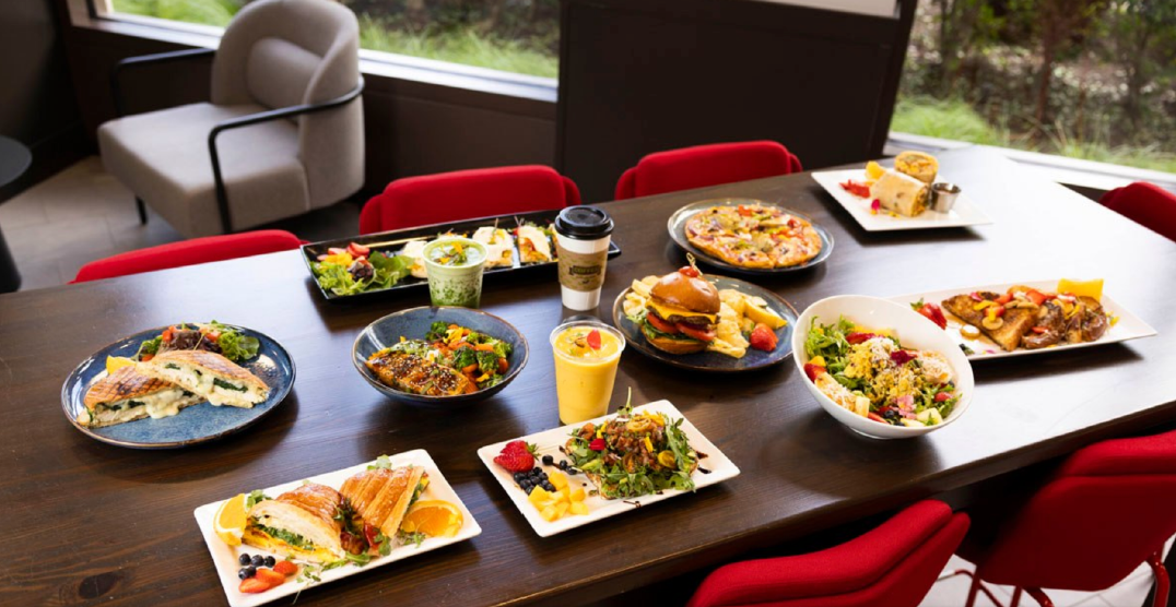 wooden table with plates of food from panini, croissant sandwich, salads, french toast, pizza, burger, breakfast burrito