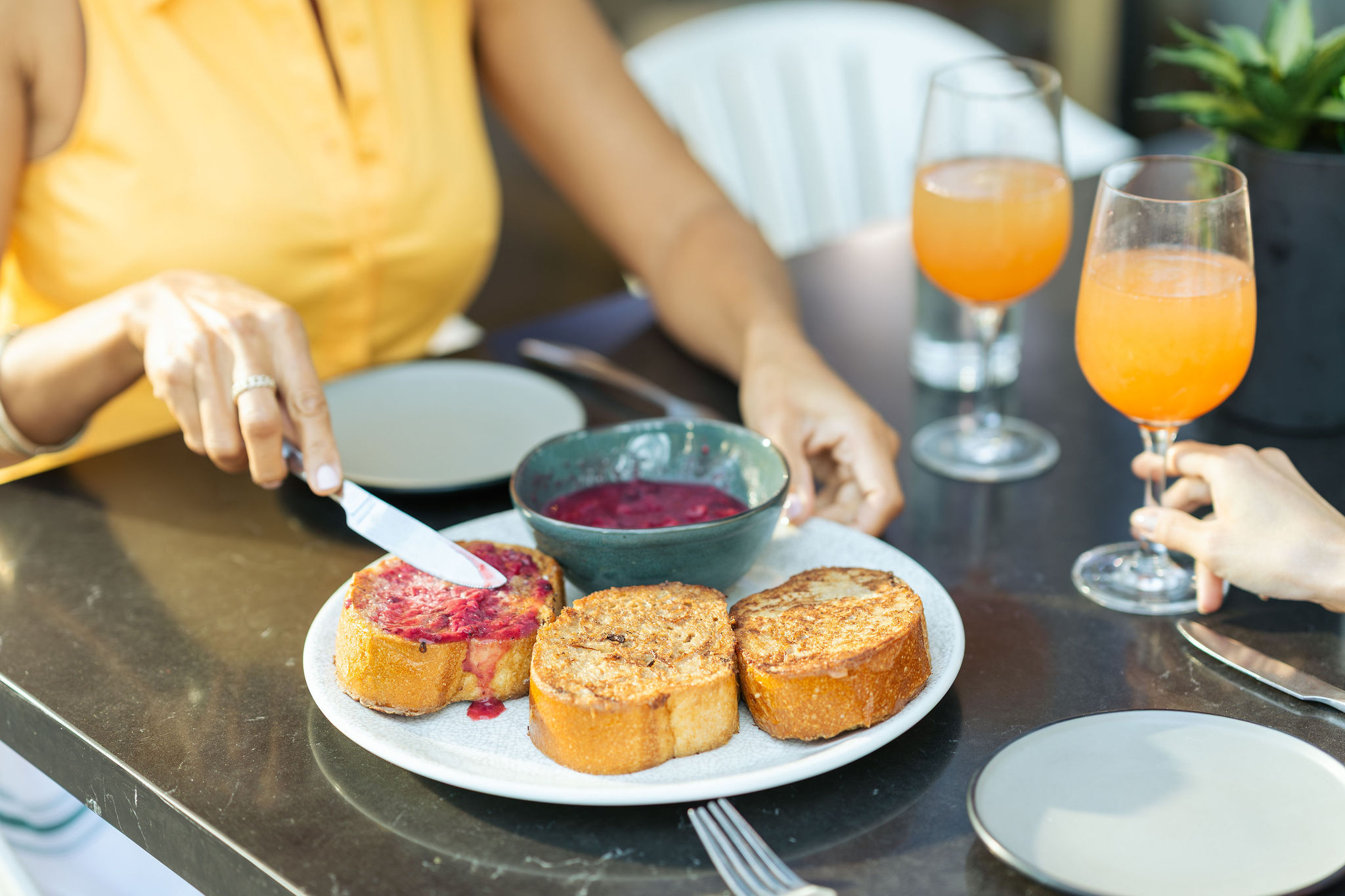 a plate of bread toast and jam with two glasses of orange juice