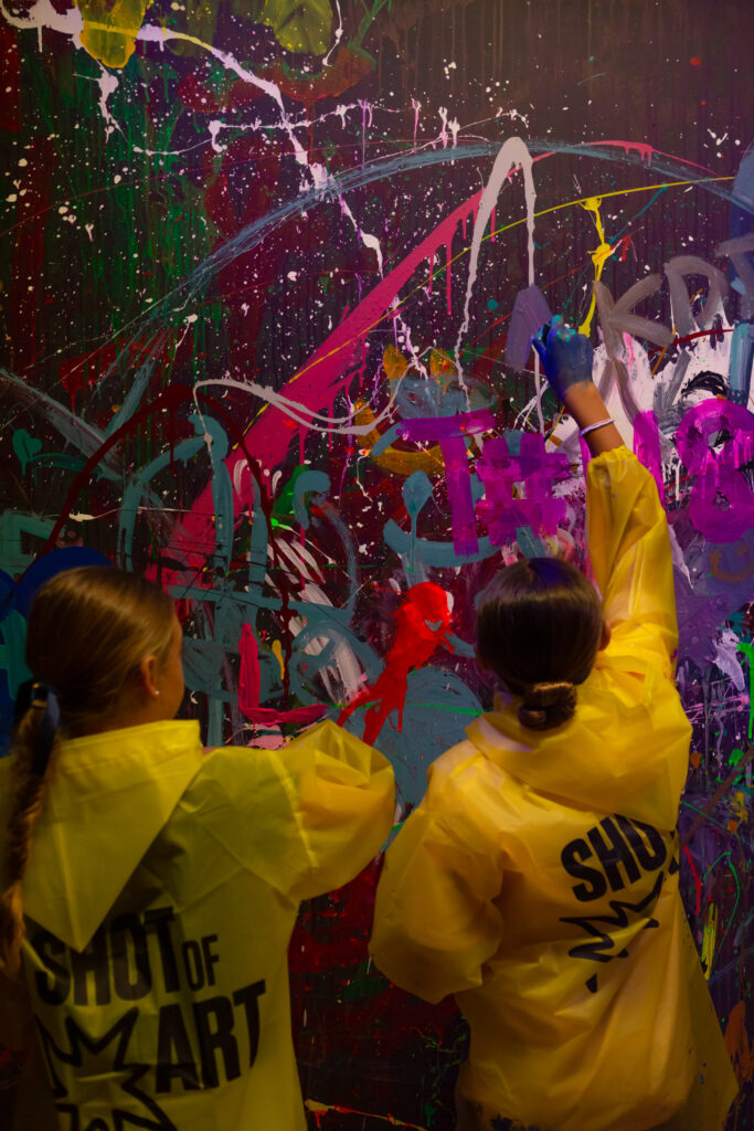 two girls in yellow raincoats painting on the wall