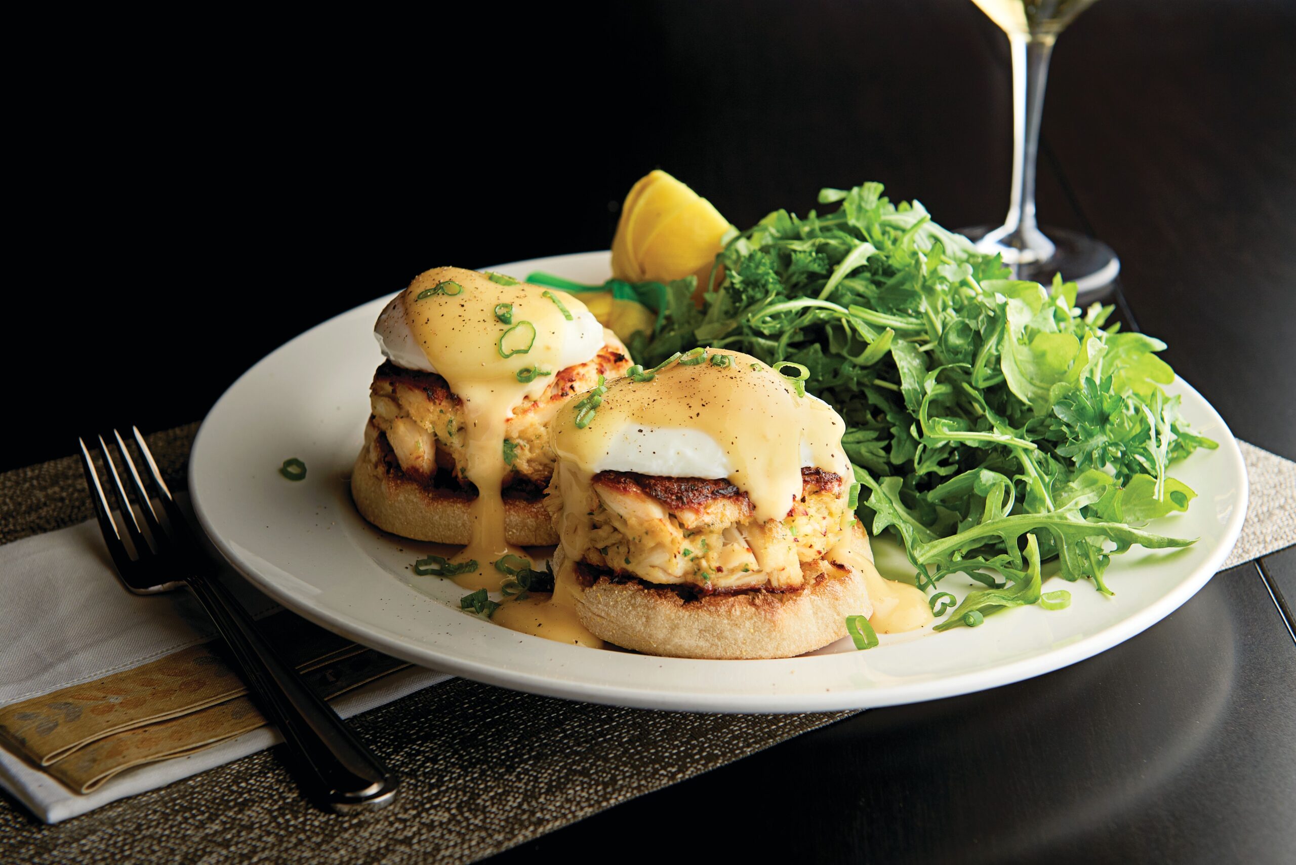 a plate of eggs benedict and greens