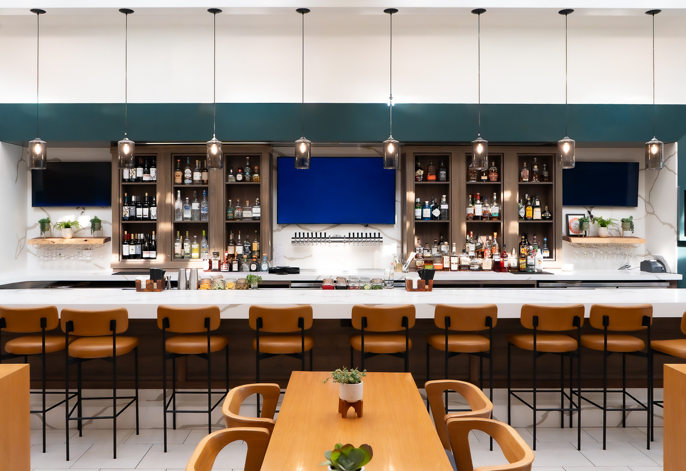 hotel bar with 3 tv screens on the wall and a display of wines on the wall as well