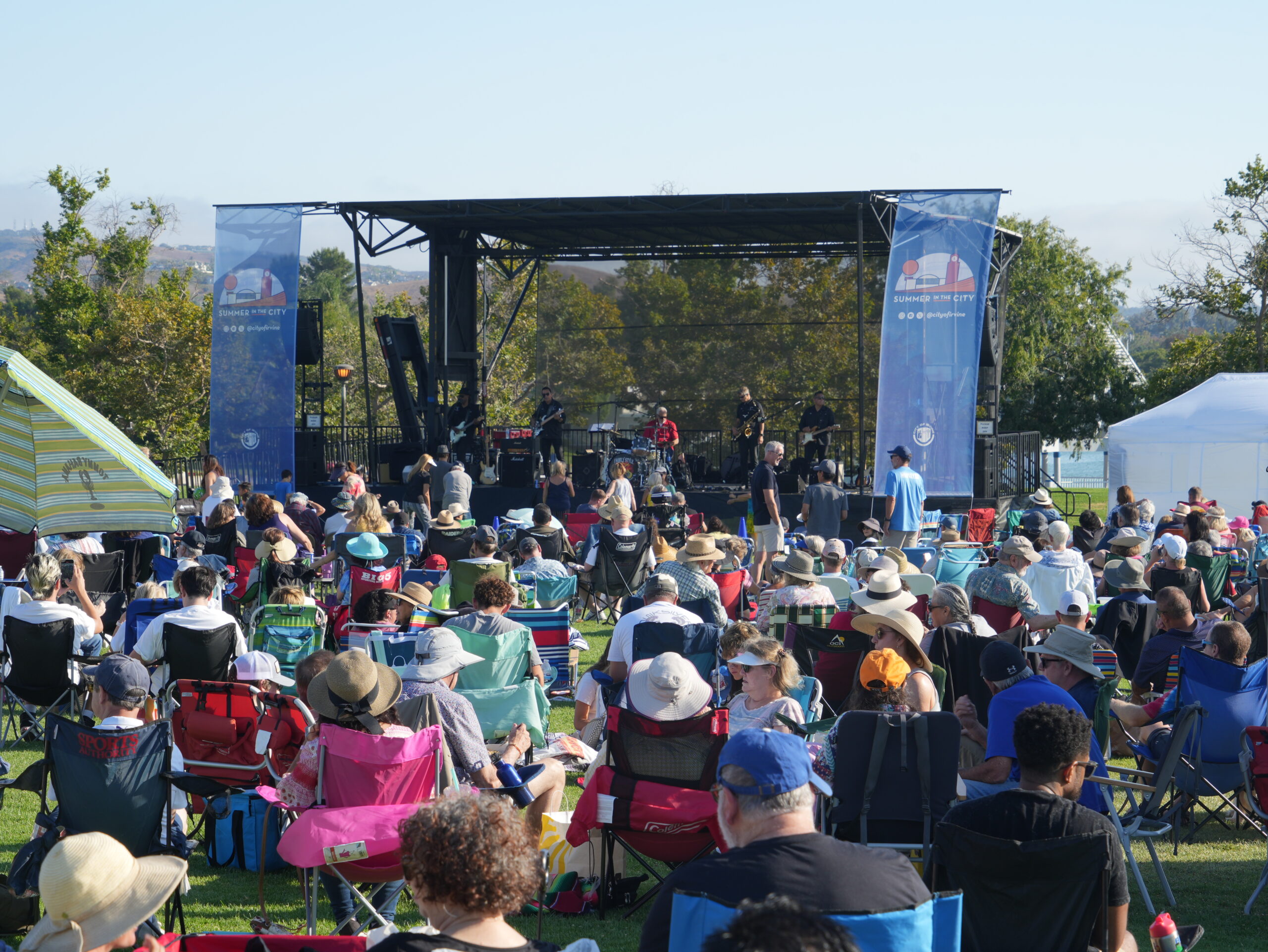 outdoor concert with people in foldable chairs watching a band onstage