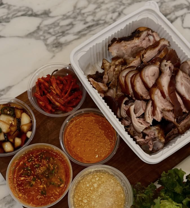 a table with a tray of pork and sauces