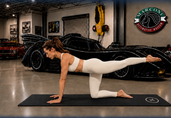 woman in white athletic gear doing pilates on a mat surrounded by cars