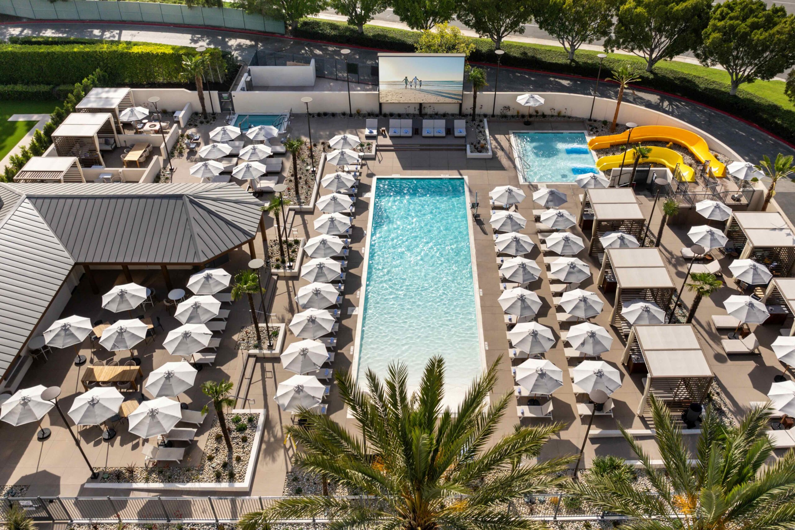 aerial view of a rectangular pool with white umbrellas lined up