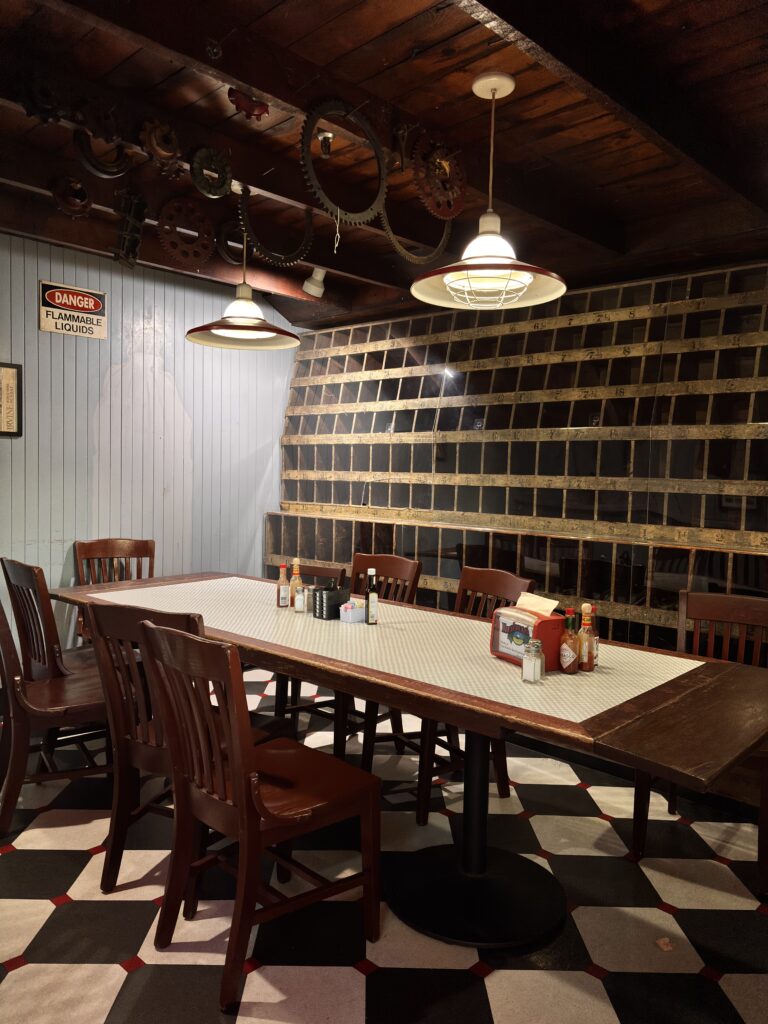 Room with rectangular table and 8 brown chairs, with two lamps from the ceiling and condiments on the table