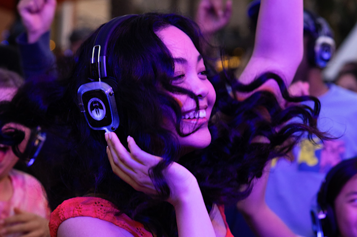 girl with black wavy hair wearing headphones smiling