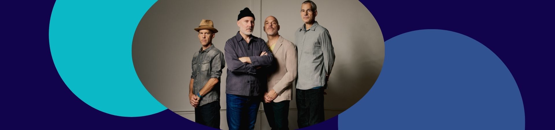 4 male performers standing and looking intently on the camera