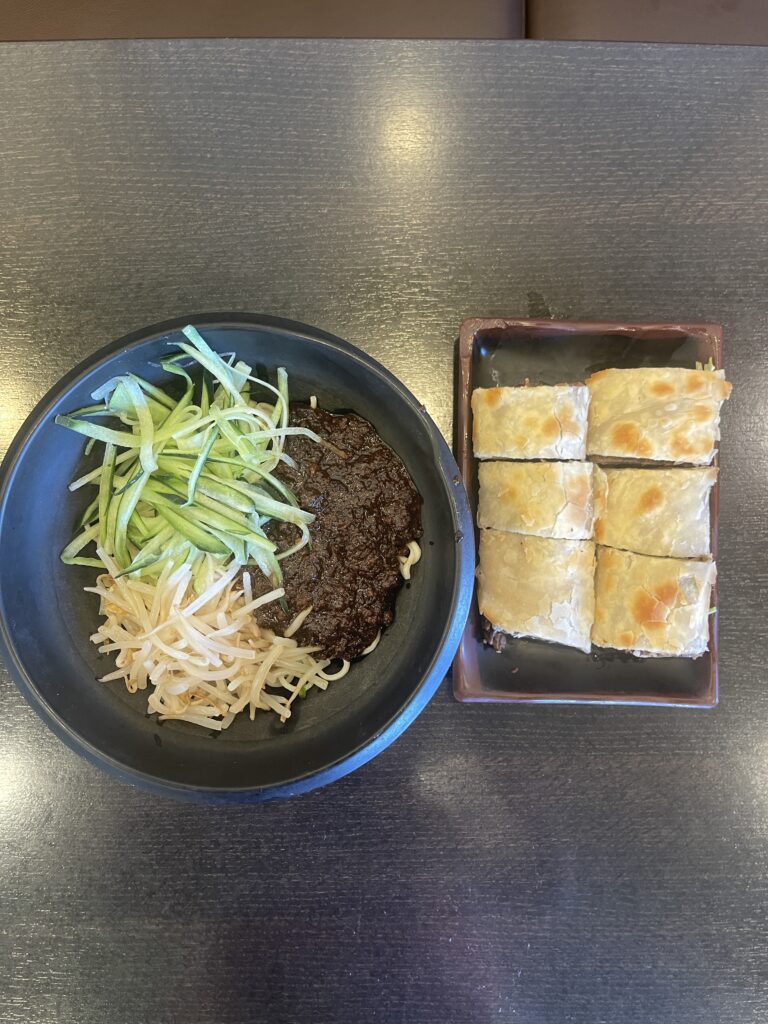 a bowl of beef noodles and a plate of beef pancake roll