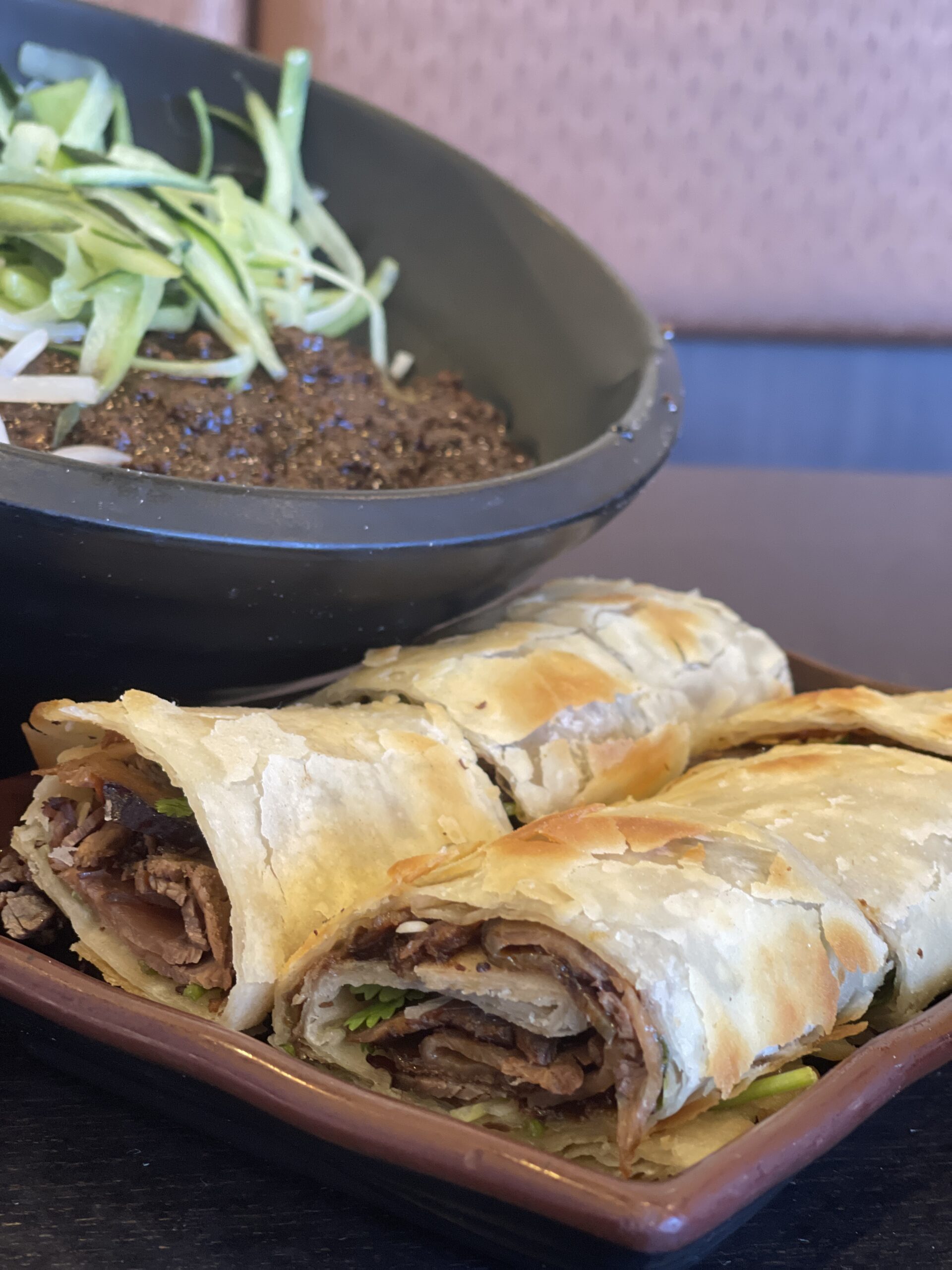 a plate of beef roll pancake and a bowl of beef noodle soup