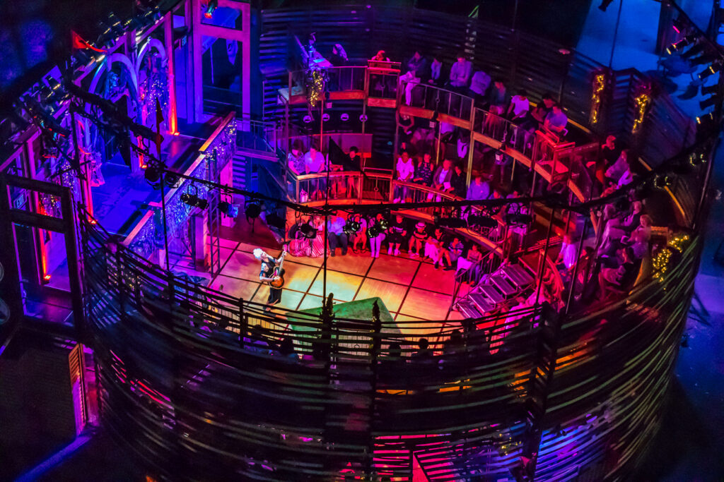 aerial shot of enclosed theater with performer and patrons sitting on the side