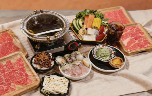 a table set up for hot pot with fresh vegetables and raw meats